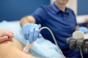 un medico specialista che esegue un'ecografia mammaria durante la prima visita senologica di una paziente
